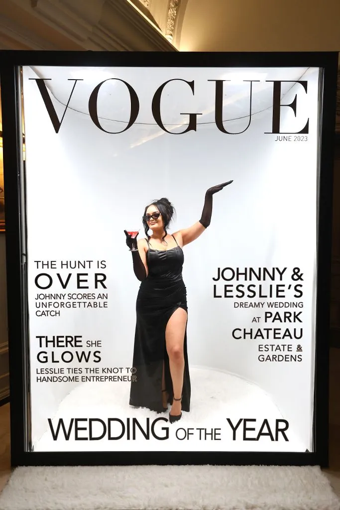 Photo booth styled as a Vogue magazine cover: a woman in a black dress holding a glass, in a bright frame