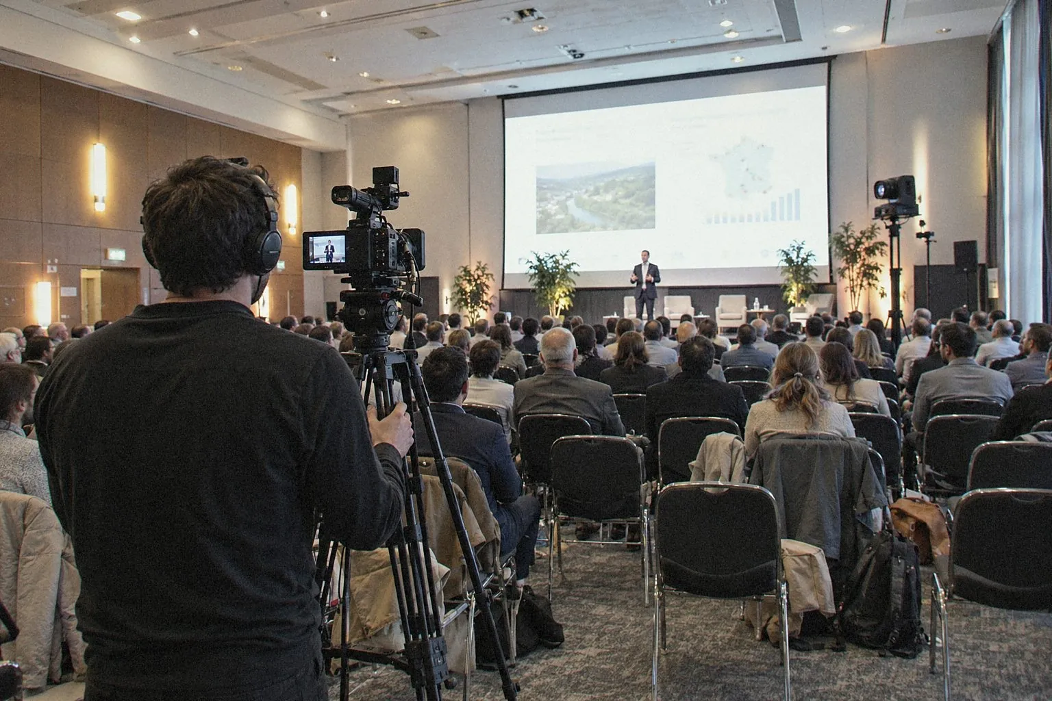 Camera and operator filming a plenary session from the back of the hall