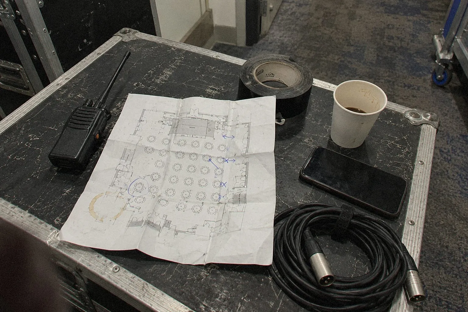 Annotated layout plan, walkie-talkie, gaffer tape and cable laid on a flight case